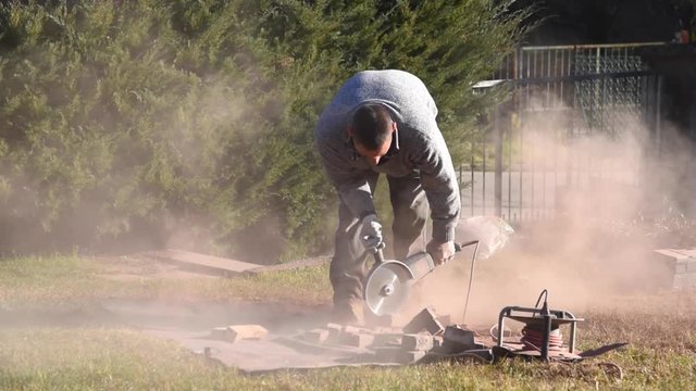 Worker cutting bricks with circular electric saw