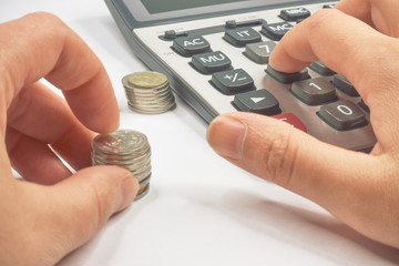 Female hand  with a calculator stacking coins into columns.
