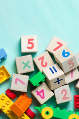 Wooden cubes with numbers and colorful toy bricks on a turquoise wooden background.