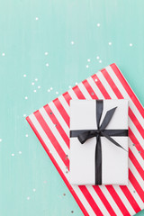 Top view on Christmas gifts wrapped in striped gift paper decorated with ribbon on turquoise wooden background with sparkling stars. New Year, holidays and celebration concept