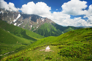 Fototapeta na wymiar Woman lies on a grass among Caucasian mountains