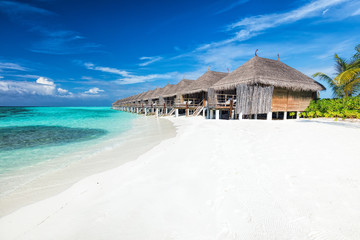 Beach and water villas on a small island resort in Maldives, Indian Ocean.