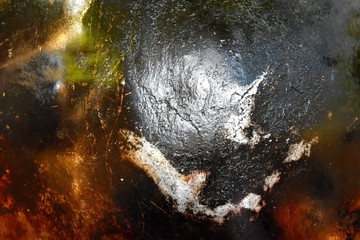 At the bottom of the pan with a soot, dirty and damaged.