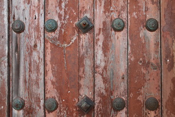Very old wooden door decorated with forged bronze nails