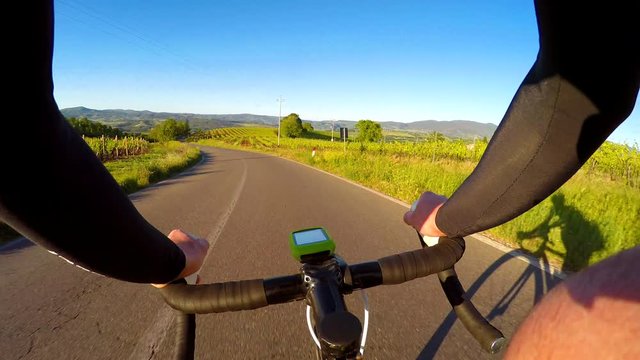 Cycling, going down by bicycle in a country road. POV, first person view.