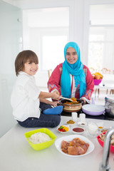 Obraz na płótnie Canvas Muslim traditional woman with little son in modern white kitchen