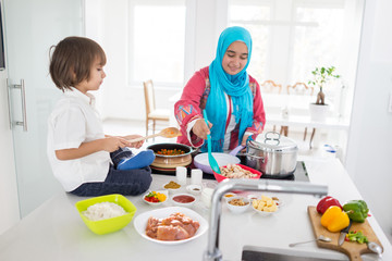 Muslim traditional woman with little son in modern white kitchen