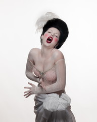 emotional brunette actress woman in a transparent lace dress and lush hair with white feathers on a...