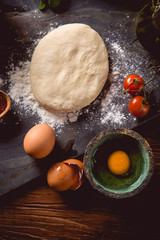 Dough with flour on wooden table, preparing homemade pizza