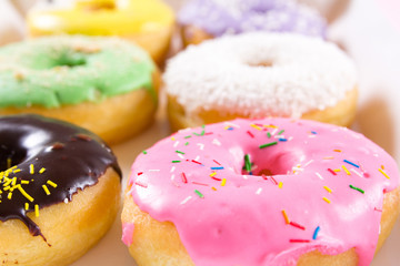 Strawberry, chocklate and other donuts in paper box on pink background