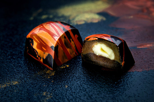 Unique handmade dark chokolate sweets on abstract painting background