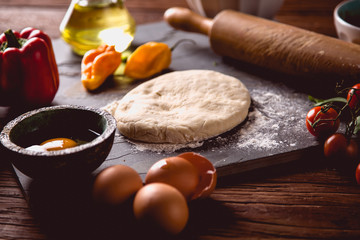 Fototapeta premium Preparing home pizza on wooden table with ingredients