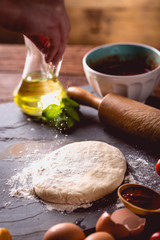 Dough with flour on wooden table, preparing homemade pizza