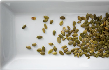 Pumpkin seeds on white tray, from above