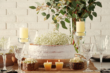 Delicious cake decorated with flowers on brick wall background