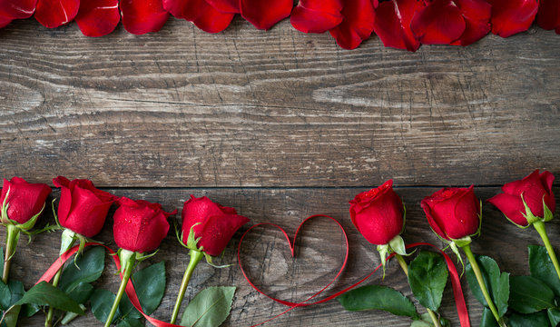 Red rose and petals over wooden background top.