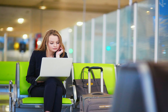 Woman in international airport terminal, working on her laptop