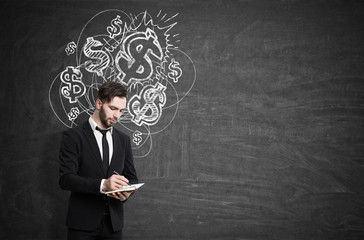 Man with notebook near dollar signs, blackboard