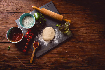 Fototapeta na wymiar Dough with flour on wooden table, preparing homemade pizza
