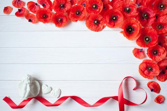 Wooden background with poppies, red hearts, ribbon