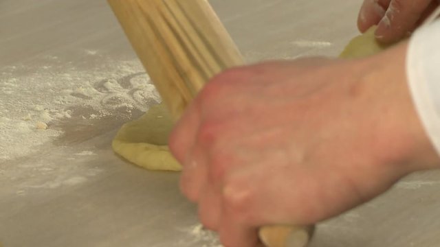 Baker rolling  dough with rolling pin 