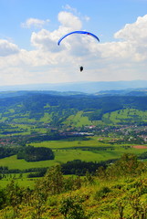 Paralotniarz nad górami na tle błękitnego nieba