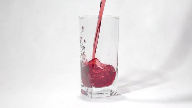 The red juice is poured into a glass in slow motion
