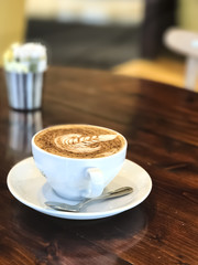 A white cup of cappuccino with a coffee art and chocolate.

