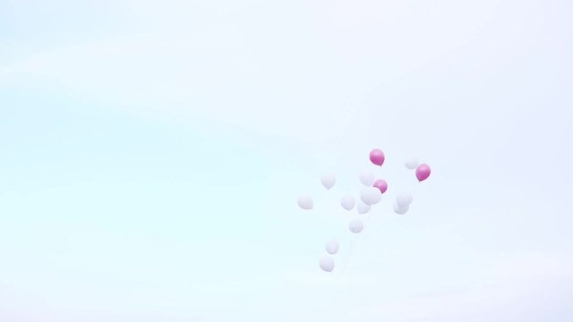 Pink and white ballons fly in the sky under the sea.