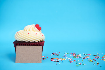 Cupcake with red heart, colorful sprinkles and brown note