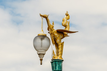Fototapeta na wymiar Public street light in Ayutthaya, Thailand, site of the country's ancient capital, just north of Bangkok. It is artfully designed as an ornamental sculpture in the form of a golden dragon. 