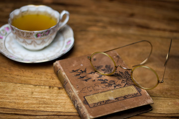 old book on the wooden desk, vintage eyeglasses, porcelain cup o