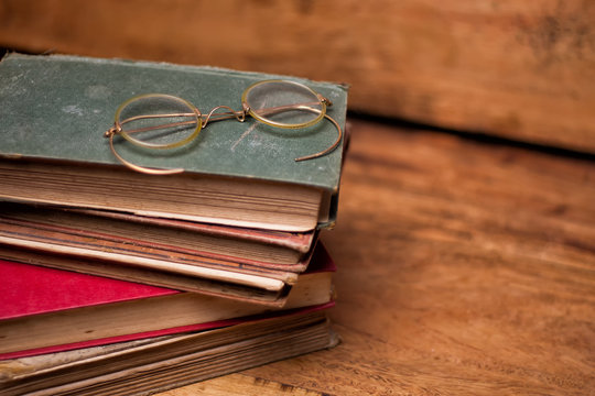  old books on the wooden bookshelfs, vintage eyeglasses