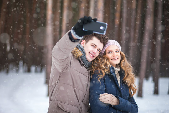 people,season,love,technology and leisure concept - happy couple taking picture with smart phone self ie stick on over winter background
