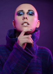 Young fashion model posing in studio. Bald. Bright make up. 