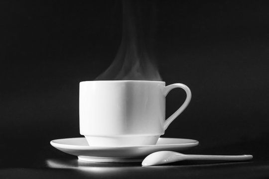 white mug with hot coffee on a black background