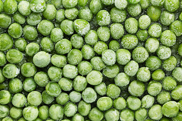 Fresh frozen green peas with hoarfrost closeup as background. Healthy vitamin food.