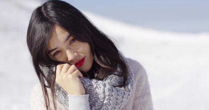 Happy cute asian girl enjoying her winter holiday time. She smiling to the camera with red lipstick on lips. Wearing warm woolen scard and sweater.