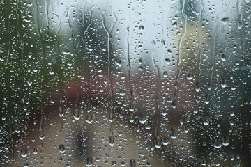 Rain drops on window with house and church in background