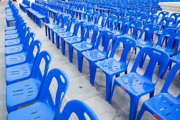 Many blue chairs on the concrete floor for viewing entertainment.