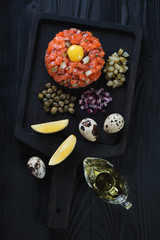 Salmon tartar on a black wooden serving tray, high angle view