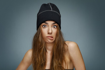 Beautiful young woman with long hair and cap makes a face