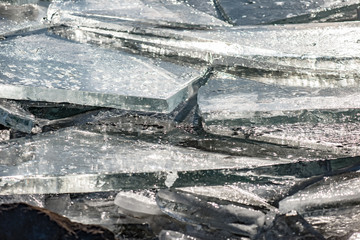 Texture of ice surface, cracked ice floating on blue water, seasonal winter landscape.