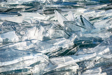 Texture of ice surface, cracked ice floating on blue water, seasonal winter landscape.