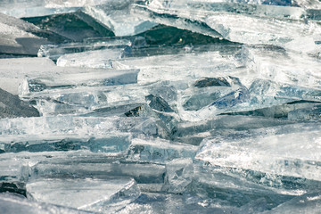 Texture of ice surface, cracked ice floating on blue water, seasonal winter landscape.