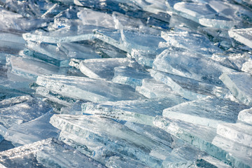 Fototapeta na wymiar Texture of ice surface, cracked ice floating on blue water, seasonal winter landscape.