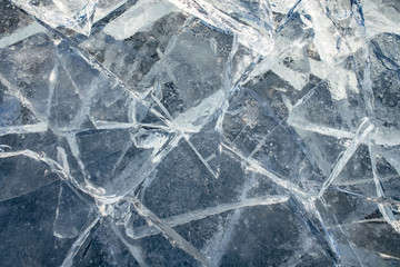Texture of ice surface, cracked ice floating on blue water, seasonal winter landscape.