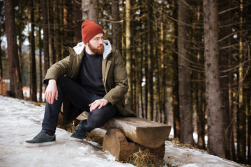 Handsome bearded man sitting over forest