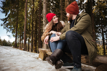 Young smiling loving couple sitting over forest and hugging