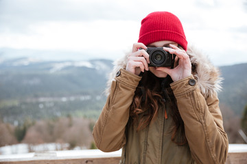 Serious woman photographer standing over mountains